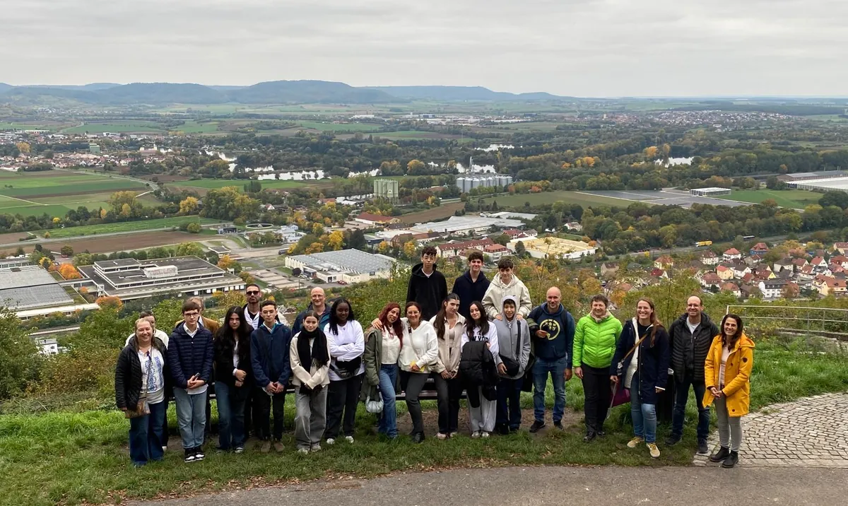Ein Teil der israelischen Gruppe steht mit Gastfamilien am Aussichtspunkt vom Zeiler Käppele, im Hintergrund sieht man die Aussicht auf die Stadt Zeil und den Steigerwald.