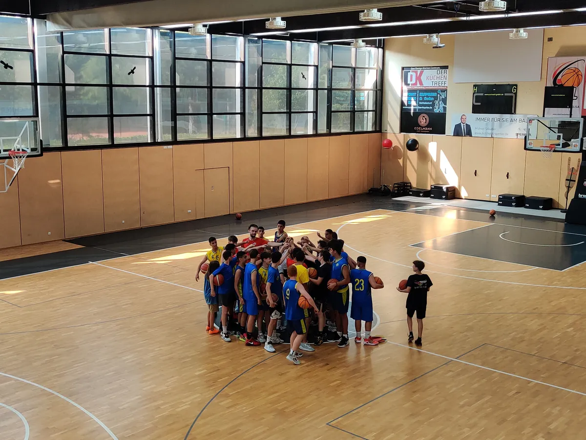 Jugendliche bei einem Basketballtraining in einer Traube im Mittelkreis