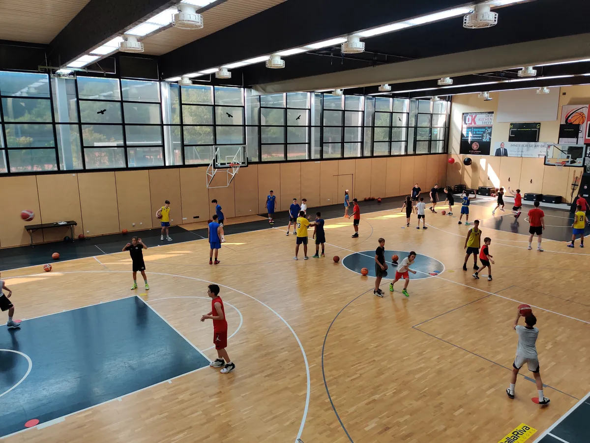 Jugendliche in einer Halle beim Basketballtraining in einzelnen Übungen