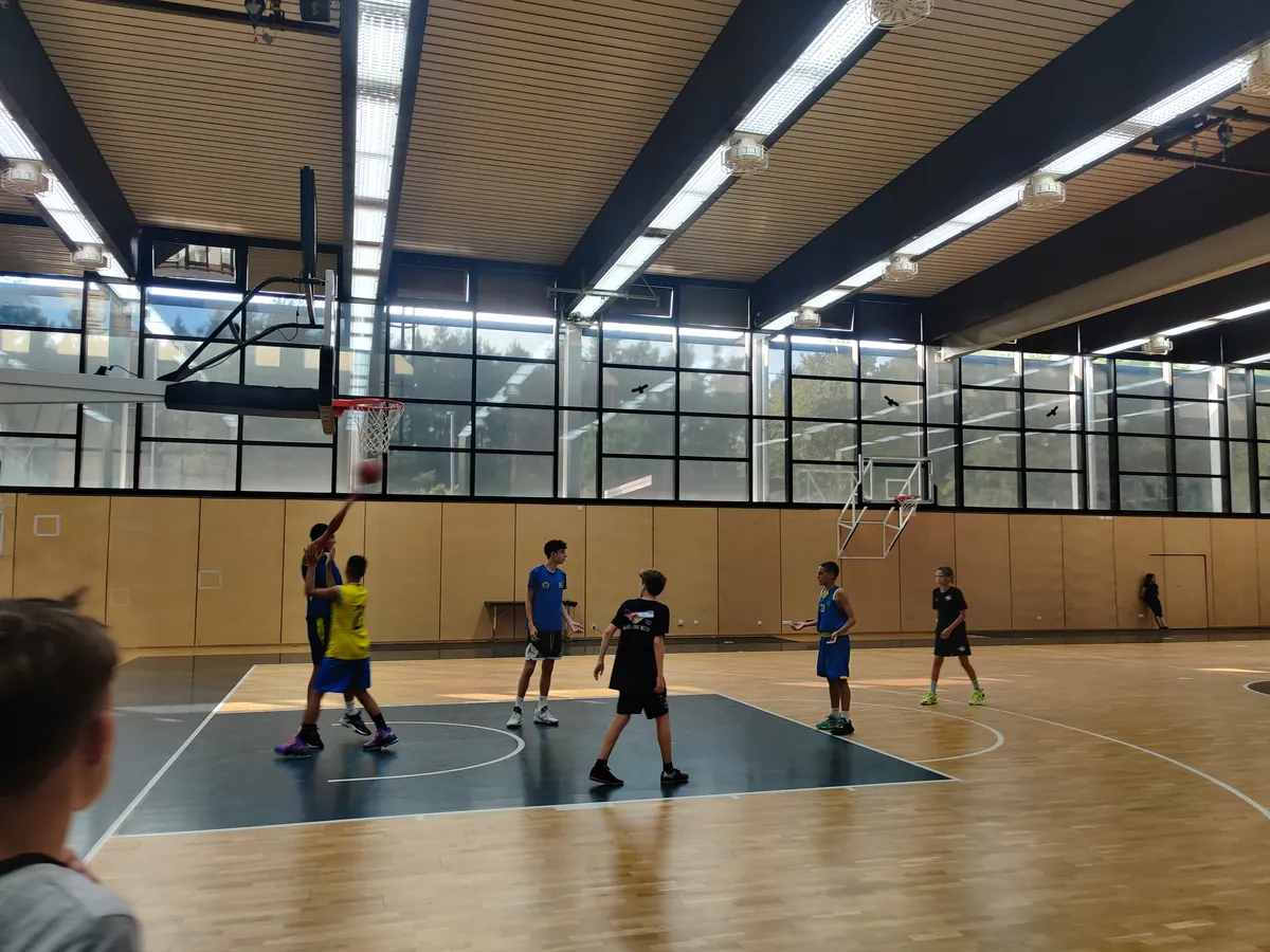 Jugendliche in einer Halle beim Basketballtraining werfen auf den Korb