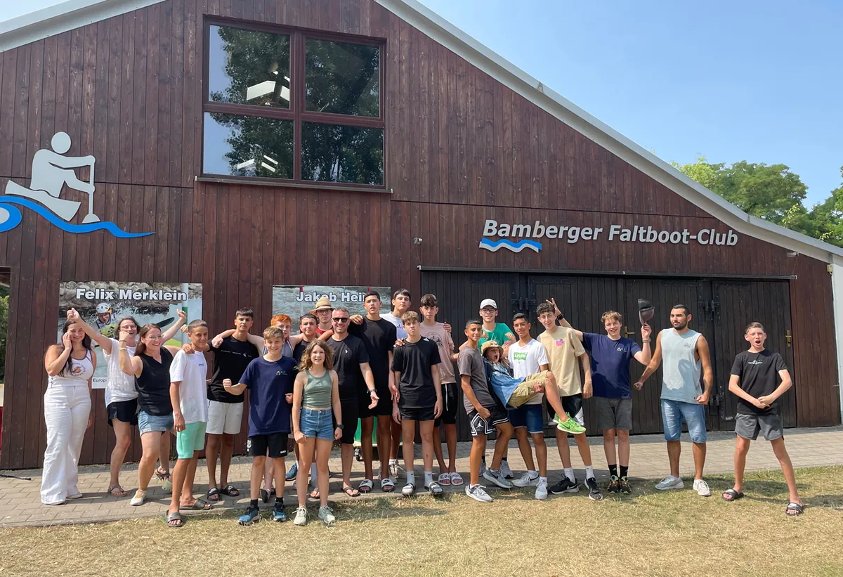 Die Teilnehmenden der Jugendbegegnung stehen vor einer Halle des Bamberger Faltboot-Clubs