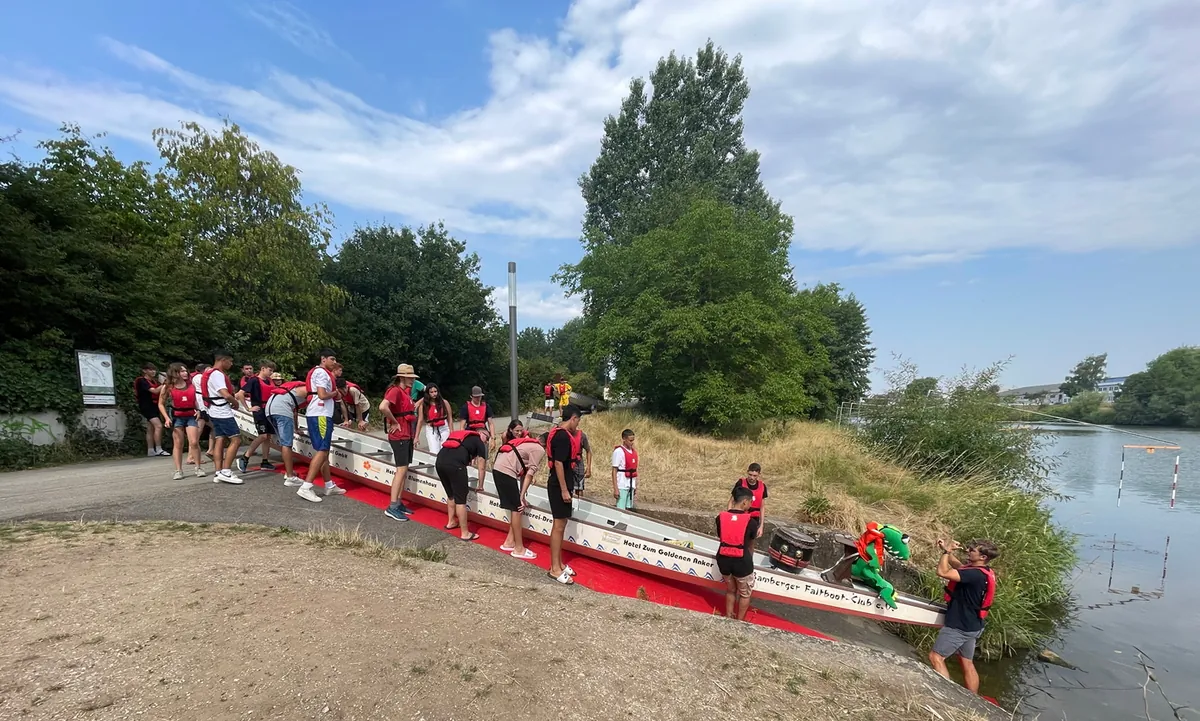 Die Teilnehmenden der Jugendbegegnung lassen gemeinsam das Boot zu Wasser