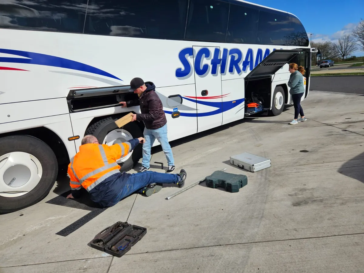 Zwei Personen versuchen Reparatur am Reifen eines großen Reisebusses
