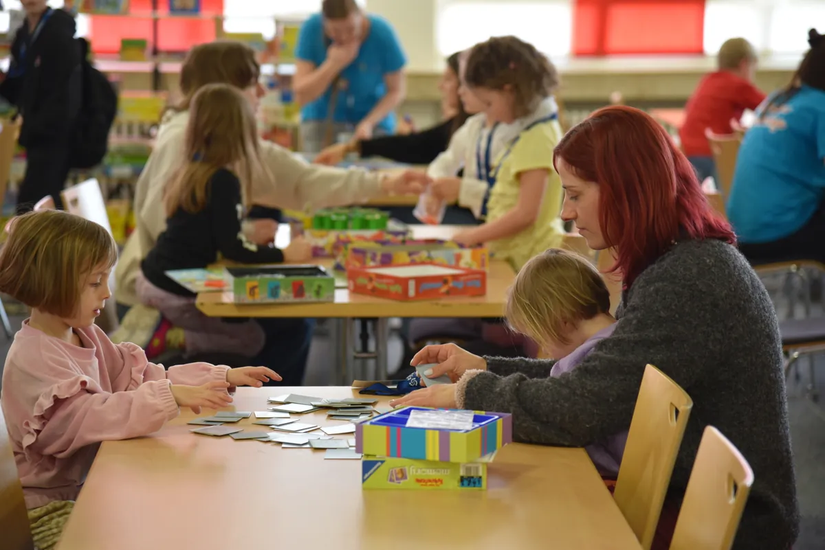 Frau spielt bei den Haßberger Spieletagen mit 2 Kindern Memory