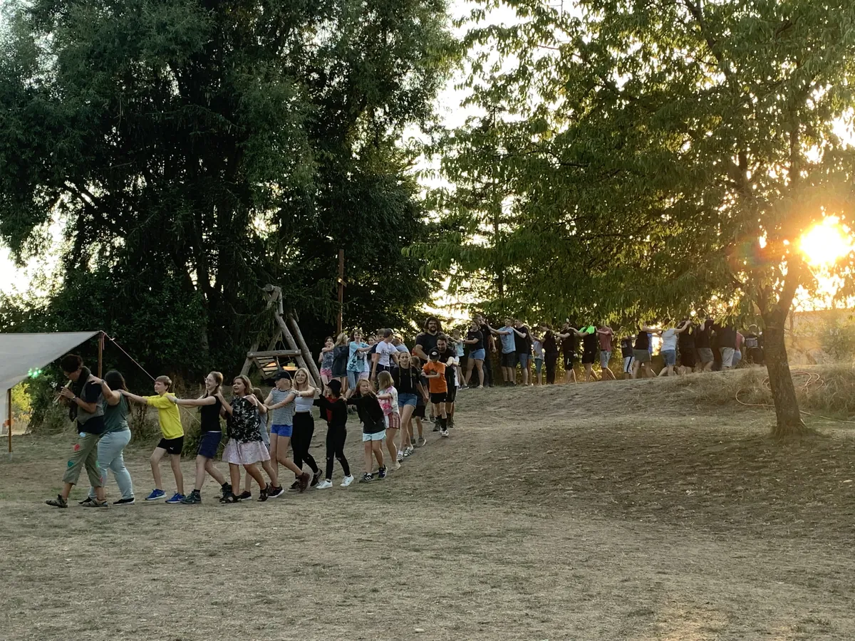Die Teilnehmer des Inklusiven Zeltlagers laufen einer Flöte spielenden Person in einer Polonaise hinterher