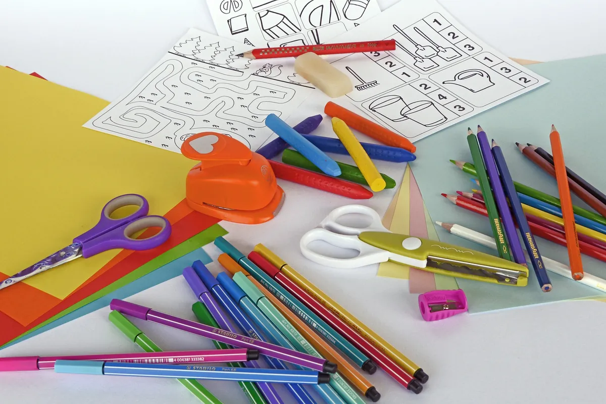 Stifte, Scheren, Locher und buntes Papier auf einem Tisch verteilt